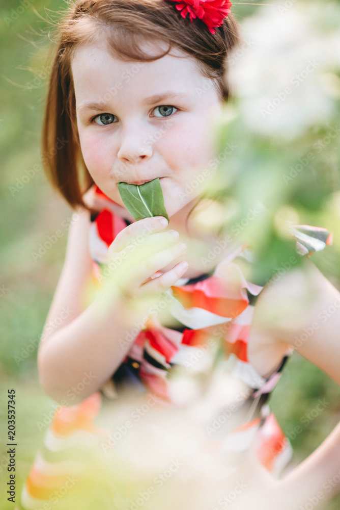 Portrait of a beautiful girl in a garden near a blossoming apple tree. Beautiful back light and happy baby in the garden Portrait of a beautiful girl in a garden near a blossoming apple tree. Beautiful back light and happy baby in the garden