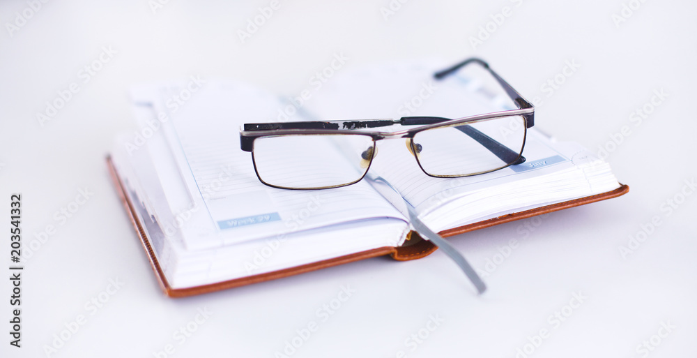 Glasses lie on the table on an open notebook Glasses lie on the table on an open notebook