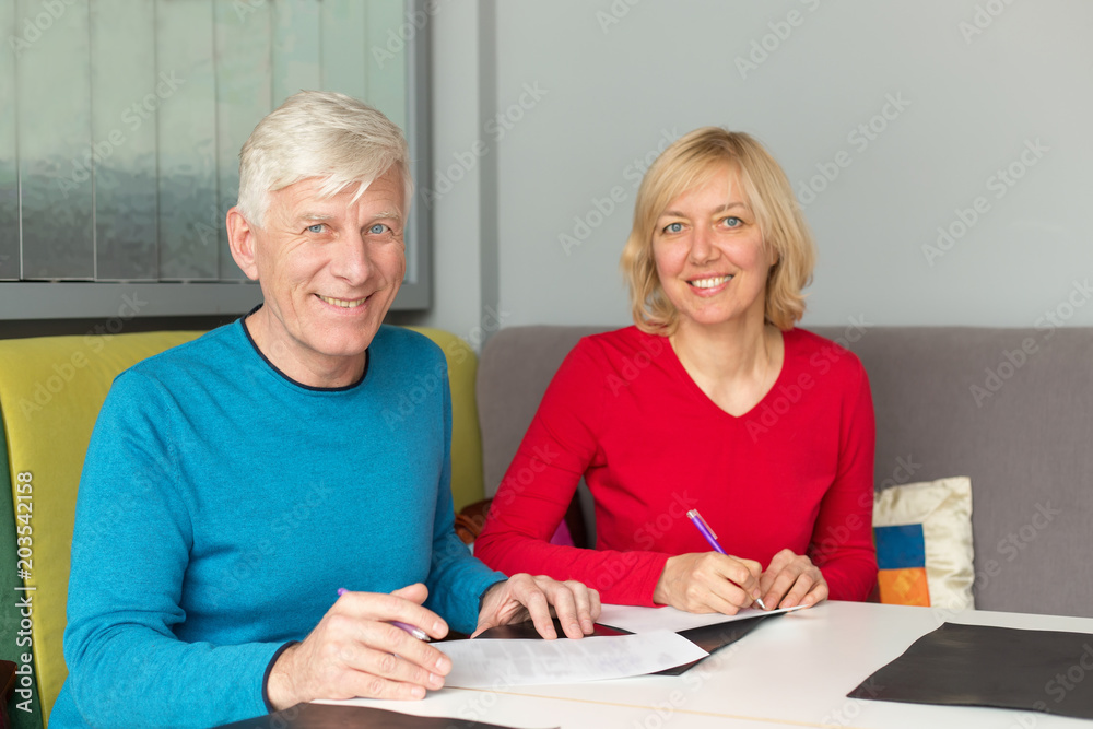 Adult couple husband and wife fill out the documents, insurance policy. Man and woman, couple pensioner aged.