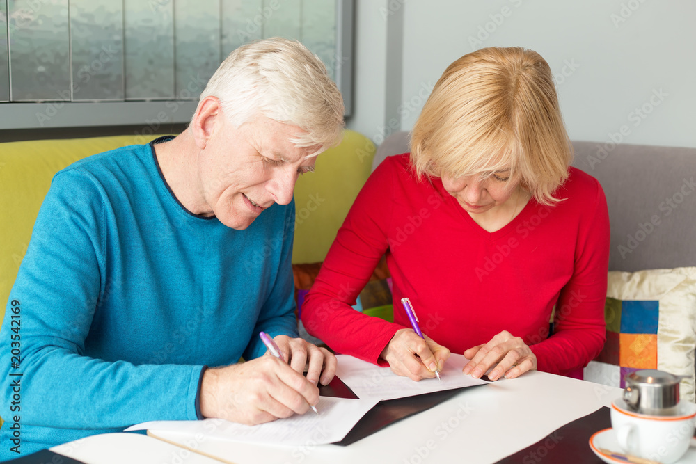 Adult couple husband and wife fill out the documents, insurance policy. Man and woman, couple pensioner aged. Adult couple husband and wife fill out the documents, insurance policy. Man and woman, couple pensioner aged.
