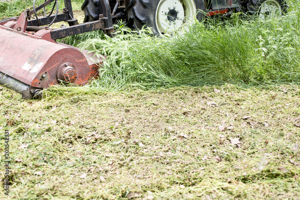 Tractor with lawn mowing grass in a Public Park Tractor with lawn mowing grass in a Public Park