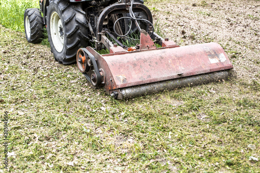 Obraz premium Tractor with lawn mowing grass in a Public Park