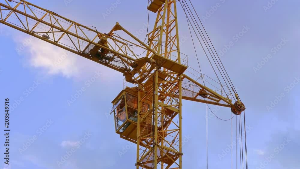 Tower crane / Crane building / Construction site. High tower crane working on the background of the summer sky with clouds. Tower crane / Crane building / Construction site. High tower crane working on the background of the summer sky with clouds.