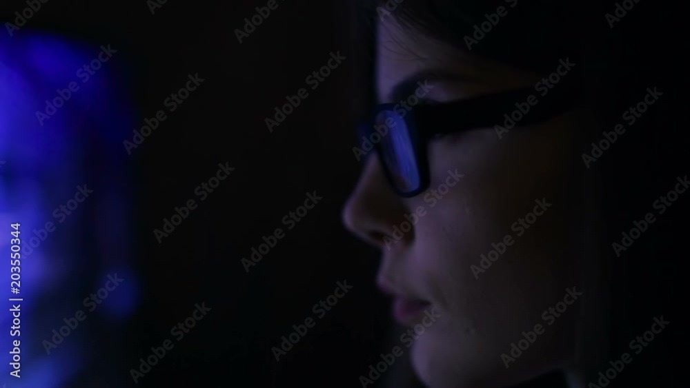 Dolly shot. woman in glasses working in the night. Reflection in glasses from laptop. Dolly shot. woman in glasses working in the night. Reflection in glasses from laptop.