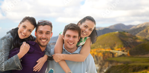 summer holidays, tourism and travel concept - group of happy friends or couples over big sur coast of california background