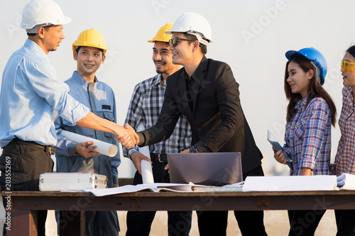 Businessman handshake with engineer with teamwork over rooftop. Success in engineering project. Architectural project achievement.