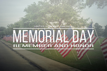 Text Memorial Day remember and honor on long row of lawn American Flags background. Green grass yard USA flags blow in the wind. Concept of Memorial day or Veteran's day in America.
