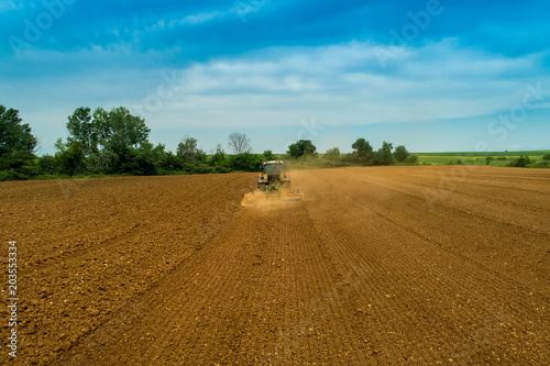 Aerial shot of Farmer with a tractor on the agricultural field sowing.