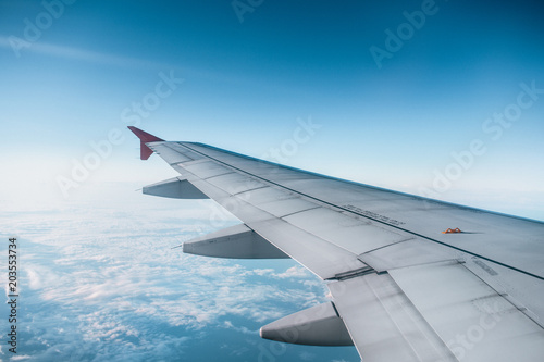"Adventure, travel, transport concept. View from plane window at sky with clouds and wing"