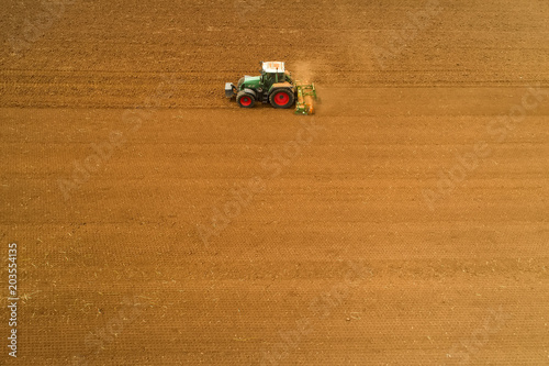 Aerial shot of Farmer with a tractor on the agricultural field sowing.