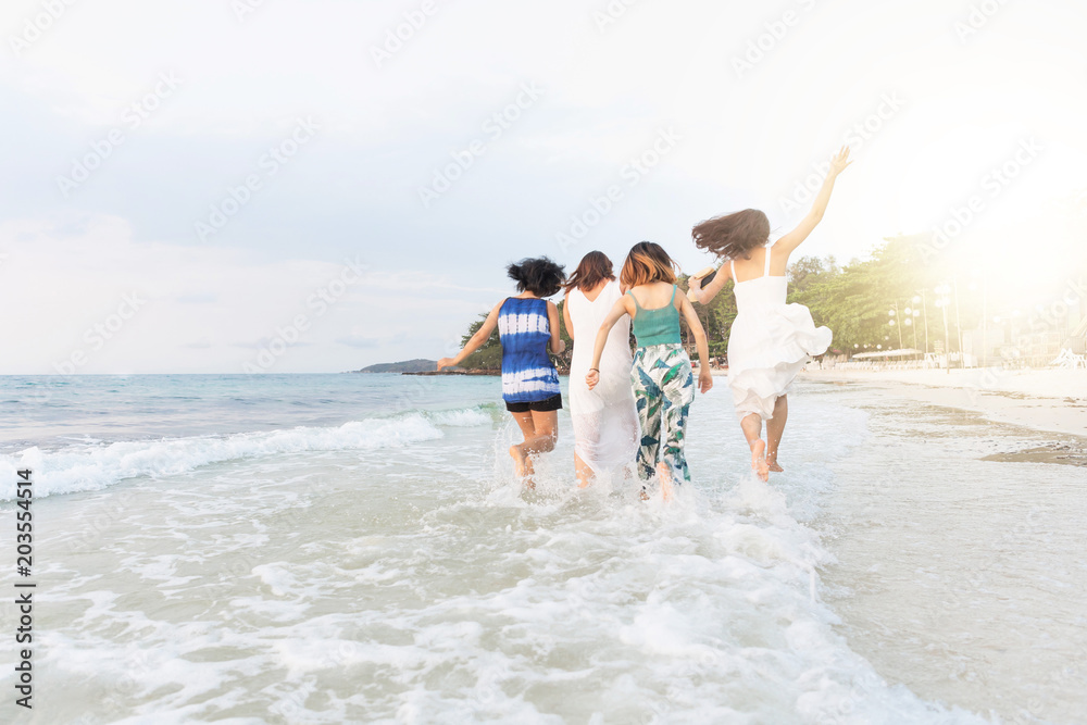 Obraz premium Summer of Happy girls running together on sunset sea beach. Holiday concept. Cinema film tone with grain.