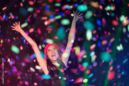 n selective focus of Cheerful young people showered with throwing confetti on a club party.Festival Event Party with People concept.Clubber drinking.