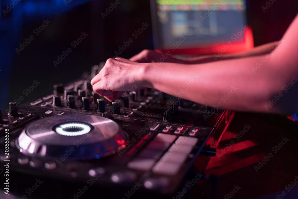 Motionblur of Dj hands on equipment deck and mixer with vinyl record at party.Closeup. Motionblur of Dj hands on equipment deck and mixer with vinyl record at party.Closeup.