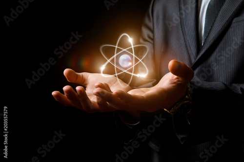 Atom in hands on dark background.