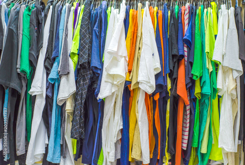 Multicolored old clothes on the hangers in the store