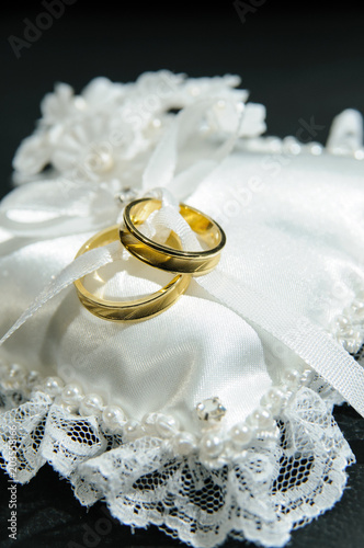 Pair of rings on white cushion. The rings represent the union of a couple.