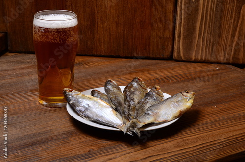 Beer with dried fish and snacks on wooden table photo