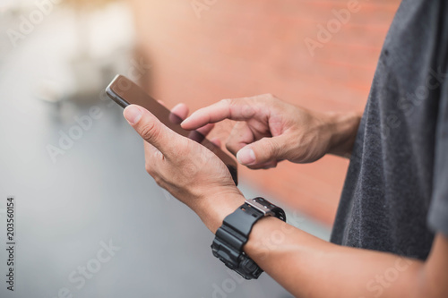 Young man with mobile phone in the street. Man uses his Mobile Phone   close up.