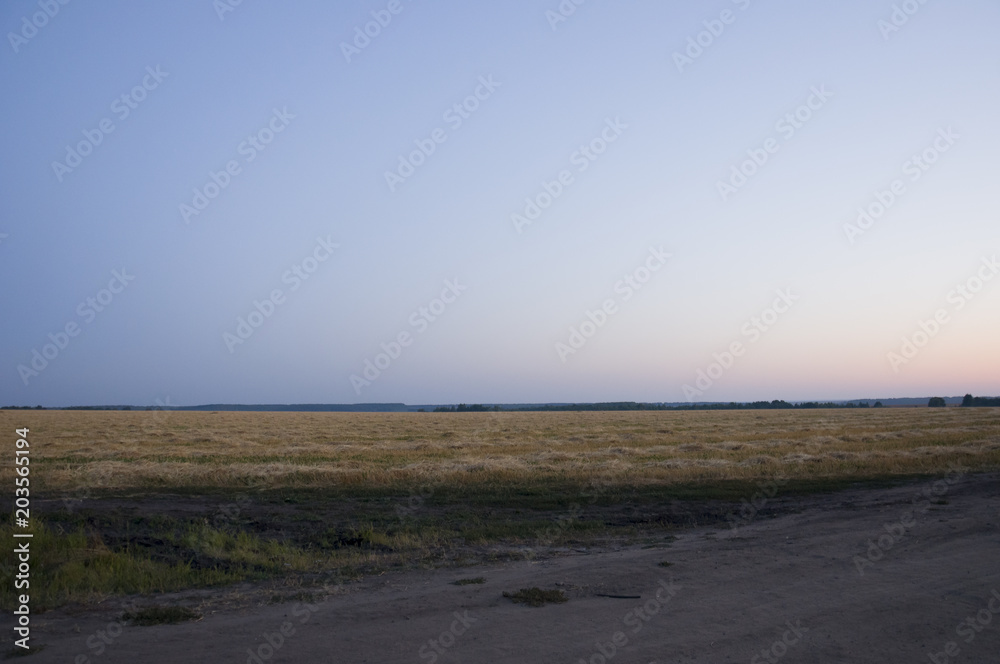 Sundown and sunrises. bright night. dark blue sky with tints of orange, red, yellow and much clouds. Silhouettes of forests far away on the background of heaven