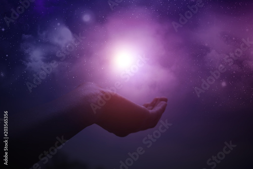 Hands holding light with night sky and stars in the background