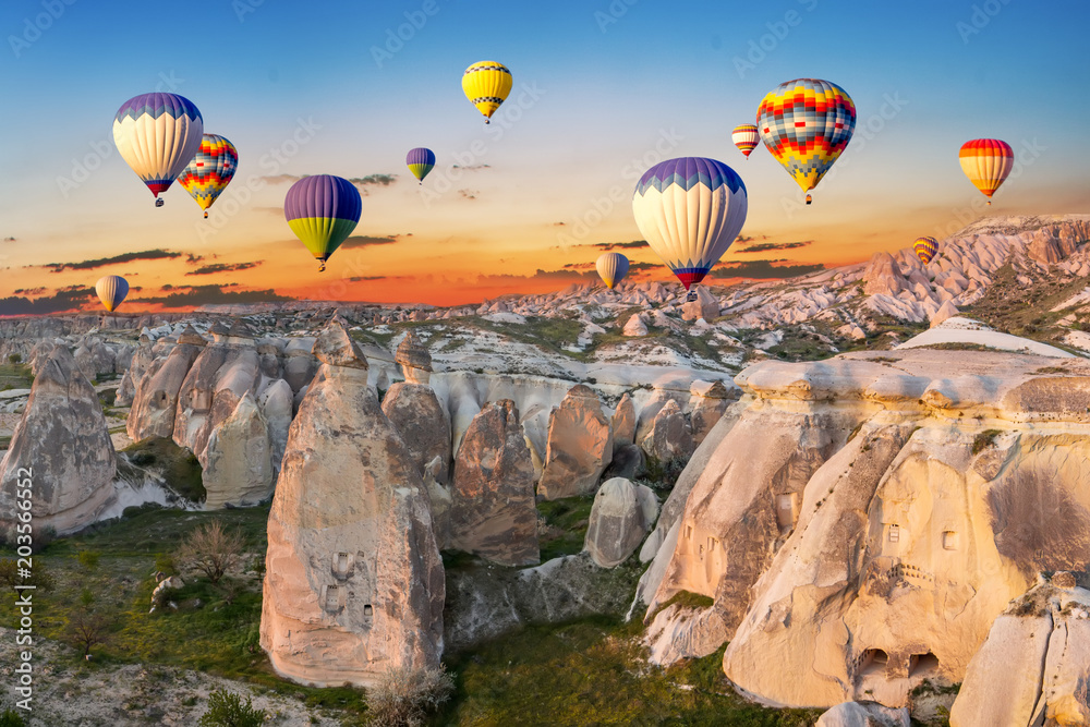 Naklejka premium Balonów na ogrzane powietrze o zachodzie słońca nad miastem jaskini, Kapadocja, Turcja