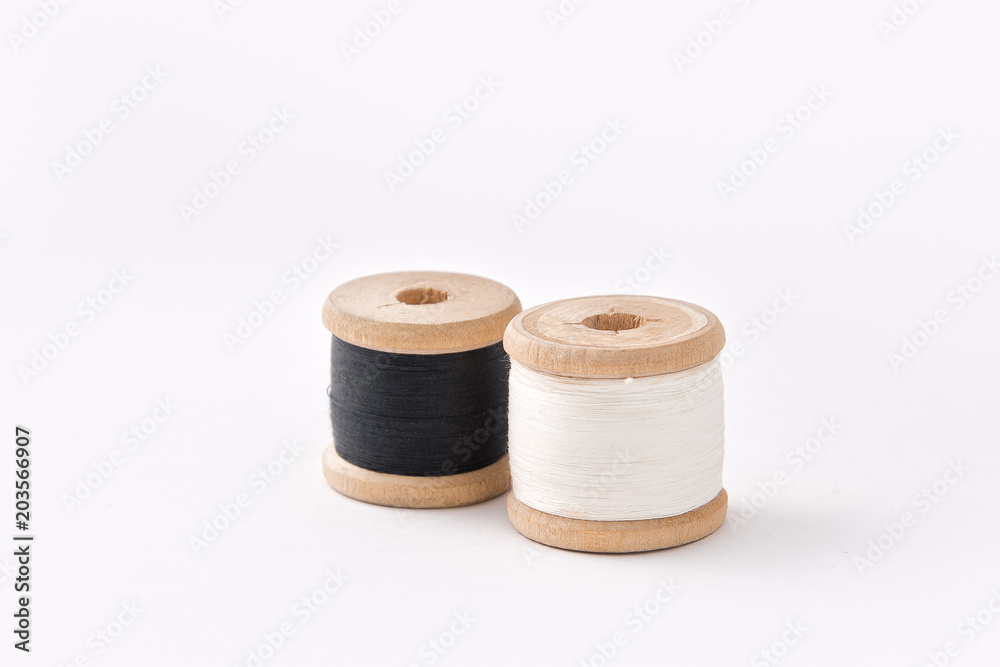 Two wooden coils with threads of black and white colours. Two wooden coils with threads of black and white colours.