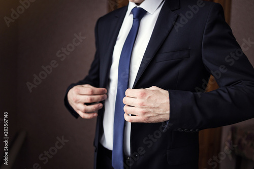 Businessman wears a jacket,male hands closeup,groom getting ready in the morning before wedding ceremony © Yuliia