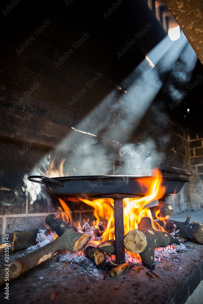 Spanish typical Paella on fire and sun ray light, side view Spanish typical Paella on fire and sun ray light, side view