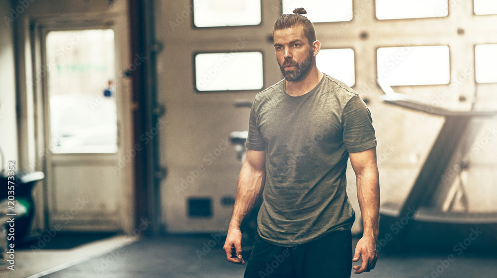 Focused young man in sportswear standing alone in a gym