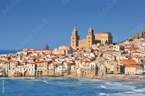 Houses along the shoreline and cathedral in background Cefalu Sicily.