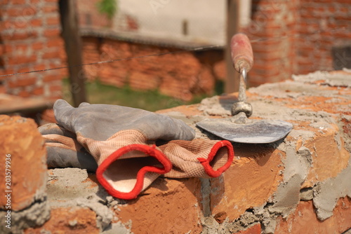 An old building tools, a trowel and gloves lying on a red bricks wall photo