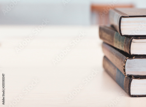 Old book stack on working wooden desk in the library room blurred image for business and education concepts background