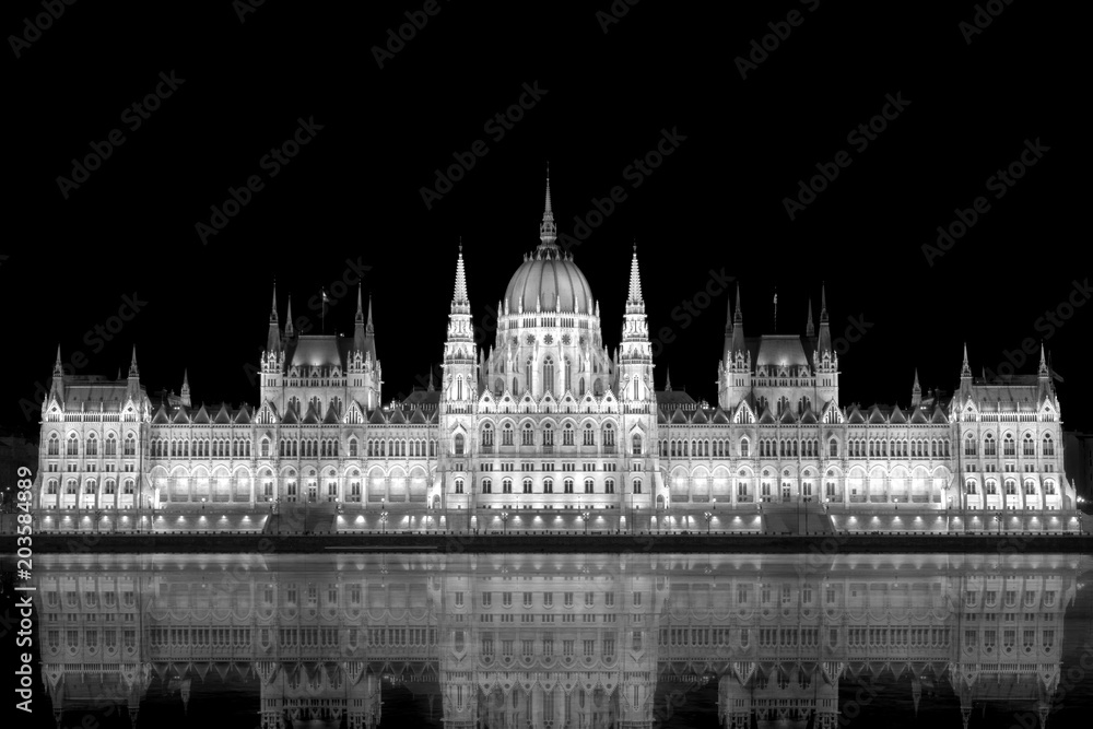 beleuchtetes Parlamentsgebäude in Budapest mit Donau im Vordergrund