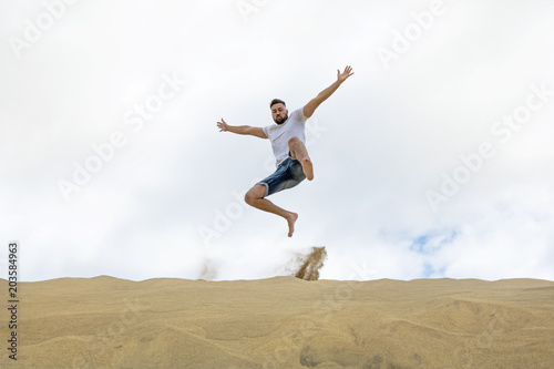 Young tourist jumping on the sand dunes.