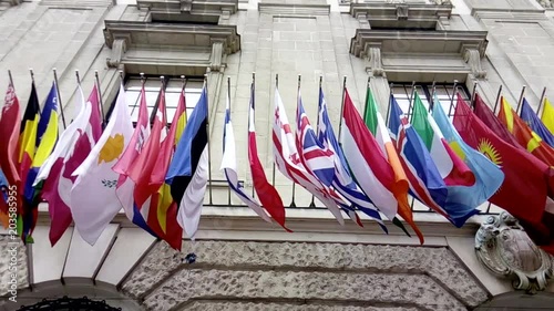 International flags from OSCE and several nations waving in the wind in front of a historical building photo