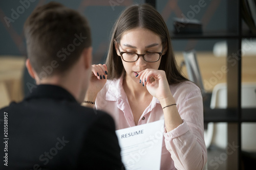 Stressed young female applicant feeling nervous at job interview while hr reading resume, unprepared candidate worried biting nails afraid of bad result at hiring negotiations, fear of fail concept