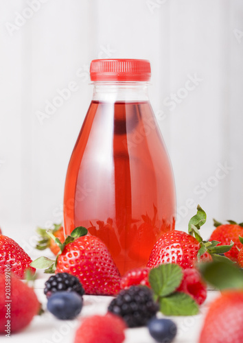 Plastic bottle of berries soda juice drink on wood