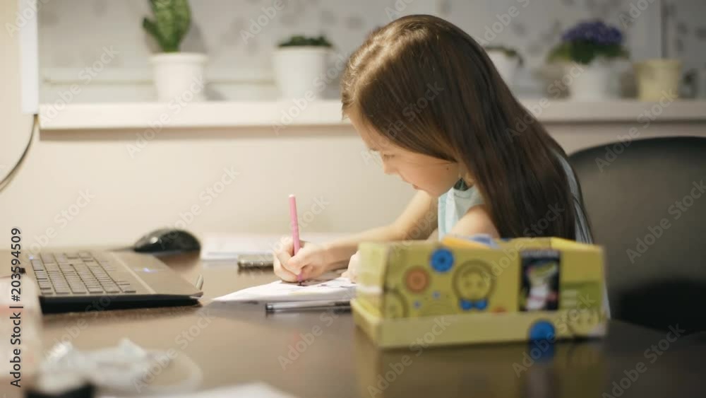 Little girl at the table draws a felt-tip pen.