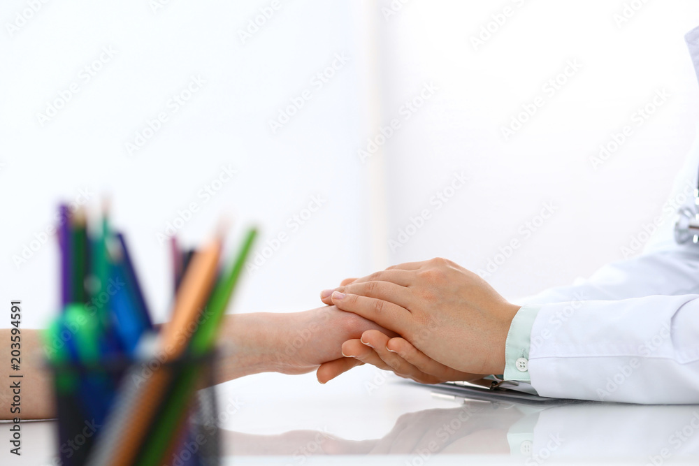 Hand of doctor reassuring to female patient, closeup. Medical ethics and trust concept Hand of doctor reassuring to female patient, closeup. Medical ethics and trust concept