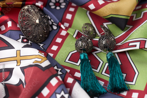 Beautiful silver earrings and a ring on a colorful fabric background. Luxury female jewelry, close-up. Selective focus