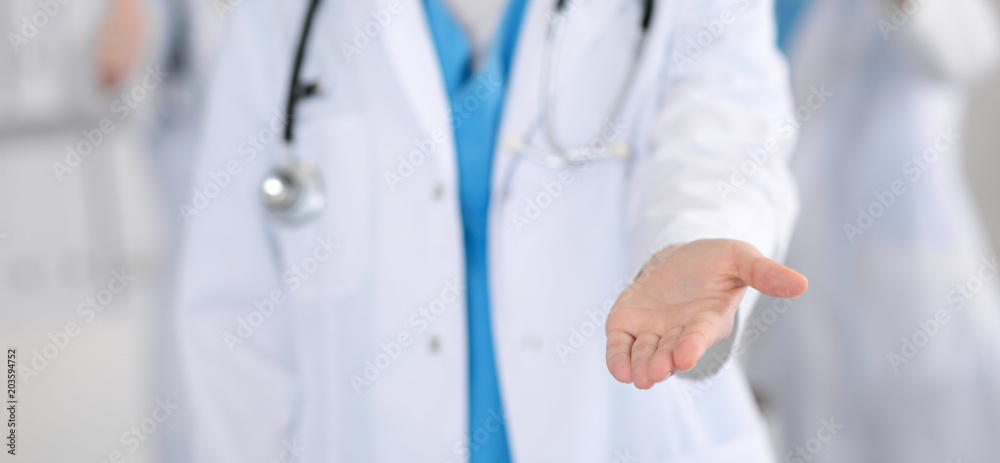Group of medicine doctors offering helping hand  for shaking hand or saving life closeup. Partnership and trust concept in health care or medical cure 