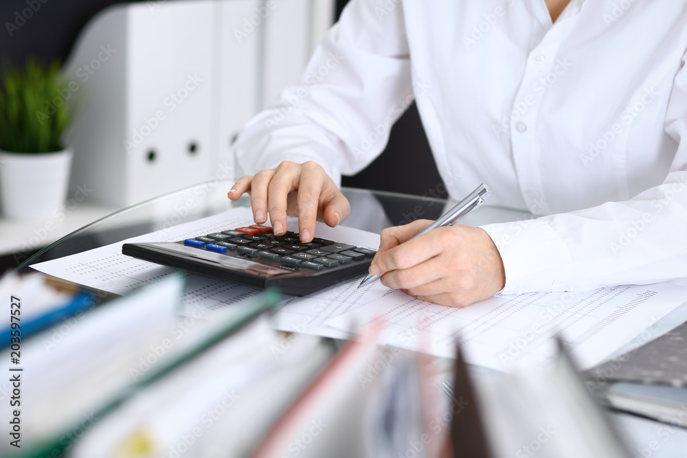 Fototapeta premium Female bookkeeper or financial inspector making report, calculating or checking balance. Internal Revenue Service checking financial document. Audit concept in business