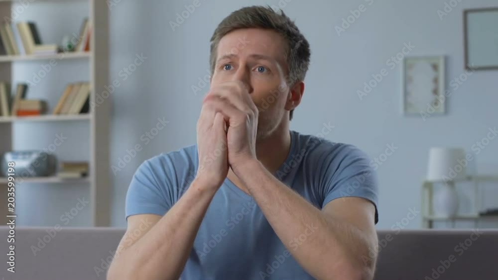 Excited male fan supporting favorite football team, watching game on TV at home