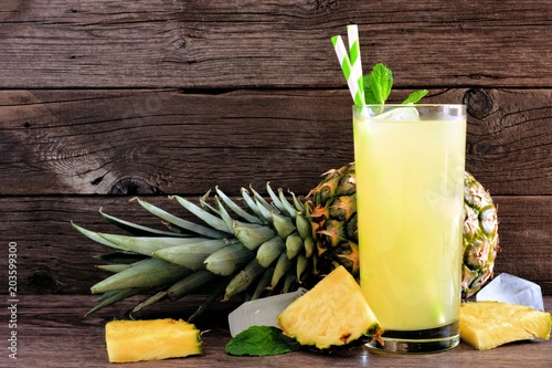 Glass of pineapple juice. Side view on a rustic wood background,