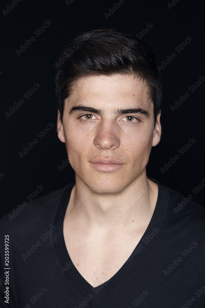 Obraz premium one young handsome man, model wearing t-shirt, simple studio upper body shot, black background.