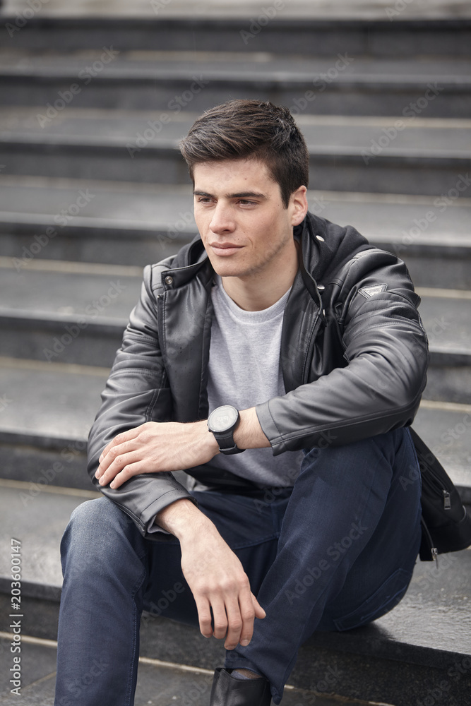 handsome man sitting on steps, wearing casual clothes. overcast autumn day. handsome man sitting on steps, wearing casual clothes. overcast autumn day.