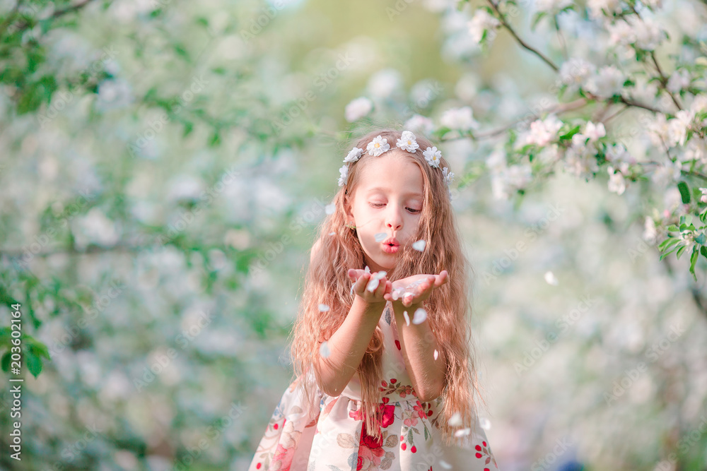 Adorable little girl in blooming cherry tree garden on spring day Adorable little girl in blooming cherry tree garden on spring day