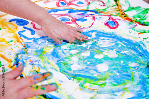 Child girl painting with colorful hands.