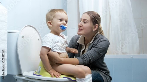 4k footage of happy young mother teaching her cute baby boy using toilet