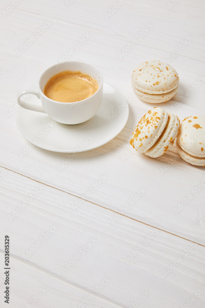 coffee cup and three macarons on white wooden table coffee cup and three macarons on white wooden table